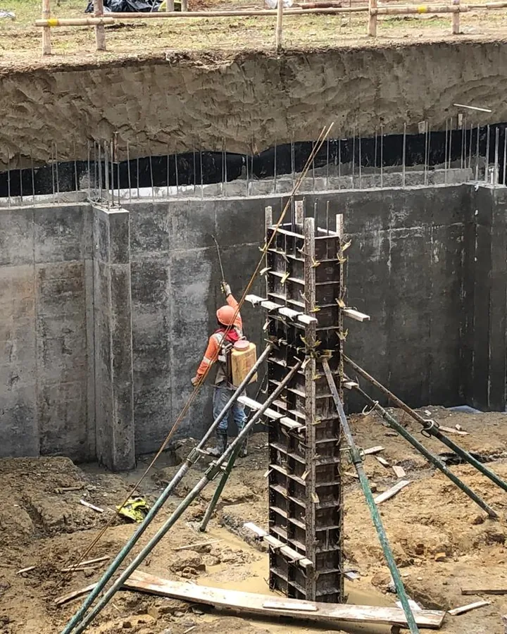 Excavación con muro de contención en concreto y el refuerzo de una columna listo para encofrar